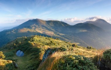 Güneşli gün yüksek dağlarda manzara güzel görünümüne çalılar ve yolu ile kaplı Yeşil Vadi tarafından açılmış.