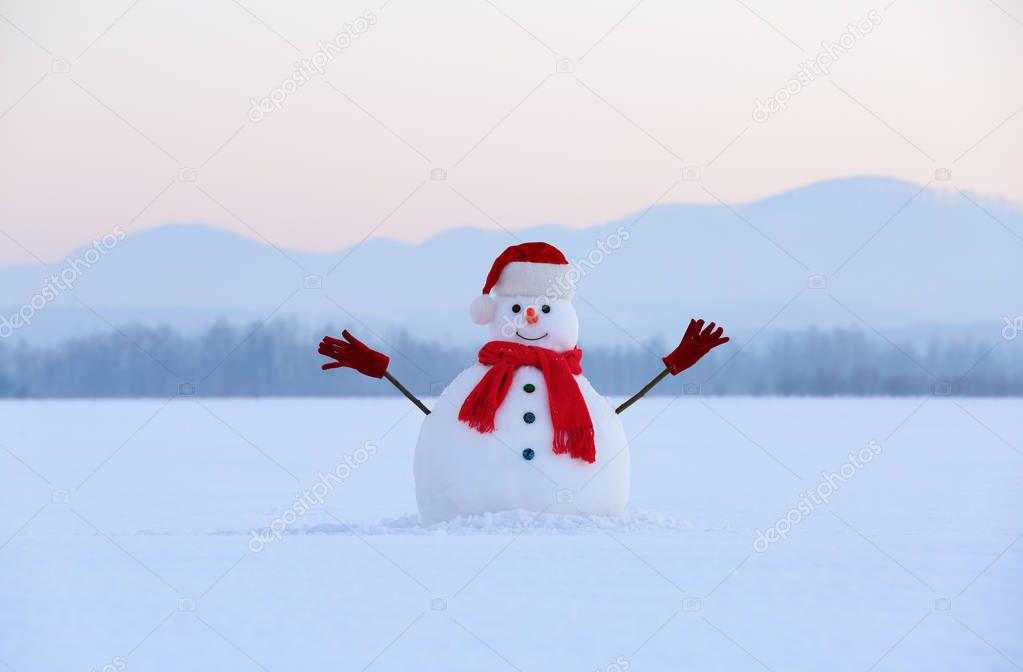 Winter scenery. Christmas snowman wearing red hat, scarf and gloves. High mountains  at the background. Nice fairy snowy day.