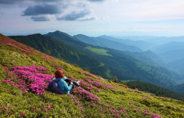 Arka çuval ve sopa izleme turist kızla ormangülü çimenlerin üzerine oturur. Gevşeme. Dağ manzaraları. Harika yaz günü. Konumu Karpat Dağları, Marmarosy, Ukrayna.