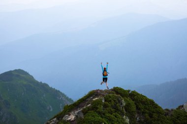 Uçurumun kenarında küçük bir çim kayalar ile vardır. Turist kız mutluluk dolu atlar. Yüksek dağlarda sis. Unutulmaz duygusal yaz gün.