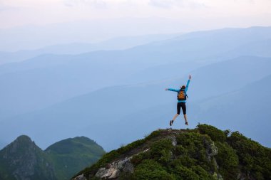 Uçurumun kenarında küçük bir çim kayalar ile vardır. Turist kız mutluluk dolu atlar. Yüksek dağlarda sis. Unutulmaz duygusal yaz gün.
