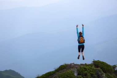 Atlama sırasında komik donmuş pozlar. Tenis ayakkabı kız. Çim taşlarla uçurumun kenarında. Dağlar çokluk. Fantastik yaz sahne.