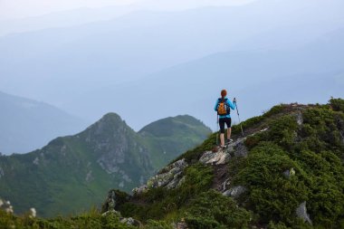 Turistik ekipman kızla çim ile kayalık yüksek tepenin zirvesine kadar gider. Sis dağlarda toplayan.