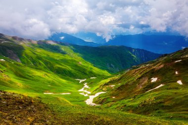 Çayır kar ile güzel bir güneş parlar, yeşil tepeler, dağlar ve bulutlu gökyüzü her yerinde vardır. Konuma yerleştirin Üst Svaneti, Georgia, Avrupa.