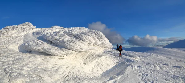 雪のパノラマをかぶった山々 織り目加工 神秘的な想像力に富む形の石 バックパックとカメラ スキー スーツの男と — ストック写真