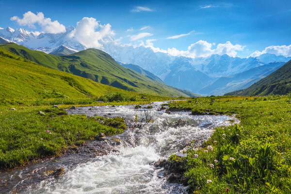 Beautiful mountain stream with colorful stones on the shore stretched among large mountains and forests. Upper Svaneti, Georgia, Europe. Happy lifestyle. Beautiful universe.