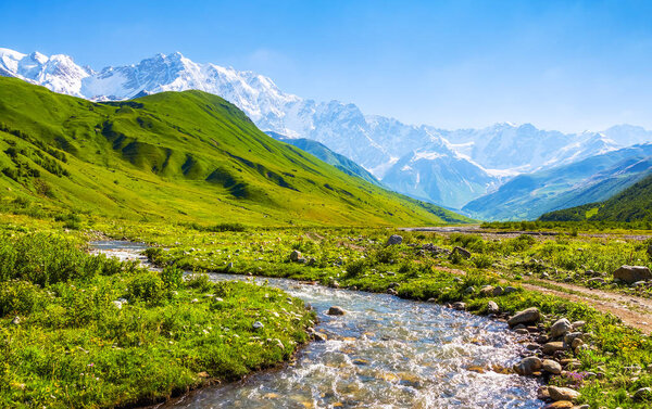 Beautiful mountain stream with colorful stones on the shore stretched among large mountains and forests. Upper Svaneti, Georgia, Europe. Happy lifestyle. Beautiful universe. 