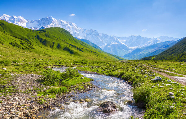 From the river shore, covered with stones, opens view on fantastic glacier and steep rocky mountains with green meadows, which are covered with snow.Happy lifestyle. Beautiful universe.