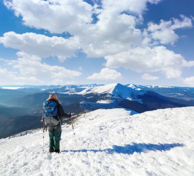 Büyük arka çuval ve sopalarla yürüyüş ile turist karlı çim aracılığıyla hedefe gidiyor ve görünümü önce orada inanılmaz güzel Dağları kar ve mavi gökyüzü ile kaplıdır