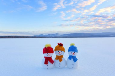 Üç küçük kardan adam renkli şapka kar bekliyoruz. Dağlar, sahne alanında kar, mavi gökyüzü. Güzel kış günü.