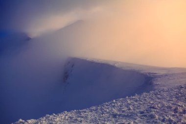 Yüksek dağ Güneş artıyor ve harika renk ile her şeyi aydınlatır. Dağlarda kar vardır. Birisi kaya arasındaki sınırda kalıyor. İnanılmaz kış manzarası.