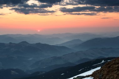 Kar kapalı çayır sabaha yanar dağlar, panoramik bir görünümünü açar güneş ışınları. Güneş doğuyor. Gökyüzü bulutlu. Büyüleyici bahar manzara.