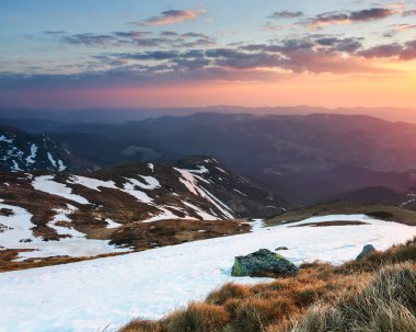Kayalar ve sarı çim çayır. Yüksek dağlar, pembe ufuk güneş doğarken doruklarına manzara. Eko turistik dinlenme. Bahar güzel gün.
