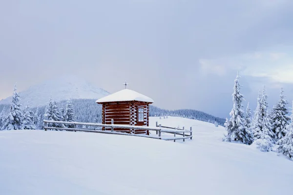 在草坪上有木制教堂里覆盖着高高山上的雪 它周围是一片美丽的树与森林 — 图库照片