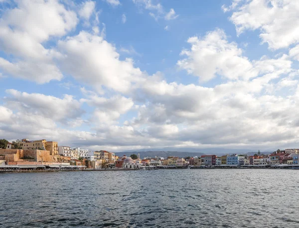 La ciudad de Chania es un puerto en la costa oeste del mar de Creta en Grecia. Una atracción turística, un muelle largo, arquitectura interesante, un edificio de baño turco, casas. Montañas en el horizonte . — Foto de Stock