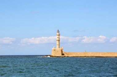 Antik tuğla deniz feneri. Turistler duvarda duruyorlar. Tatil liman Chania, Creete adası, Yunanistan için popüler bir yer. Dalgalar ile zümrüt deniz boyunca sahil. Bulutlarla mavi gökyüzü.