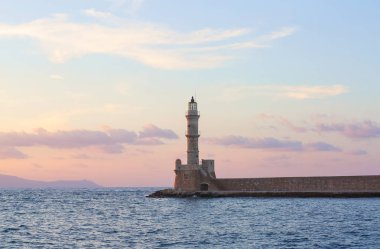 Tuğladan yapılmış yüksek, güzel, antik deniz feneri. Muhteşem gün batımı gökyüzünü aydınlatAn. Deniz kıyısı boyunca bir duvar ve yol vardır. Turistik tatil Chania, Creete adası, Yunanistan.