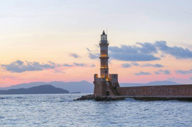 Deniz le çevrili güzel antik deniz feneri ile sahne. Pembe ışıkla gün batımı gökyüzü. Yüksek dağlar. Konumu liman Chania, Creete adası, Yunanistan.