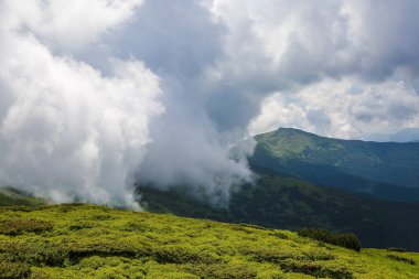 Yeşil çimlerden gizemli sise, eski binayla dağlara ve bulutlarla dolu ilginç gökyüzüne inanılmaz bir manzara..