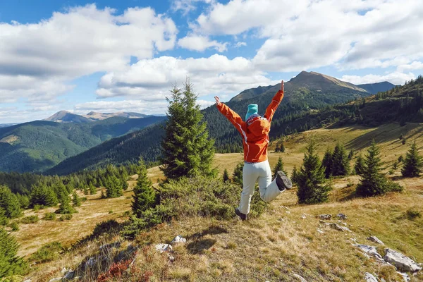 快乐的女运动员在草坪上跳着。 秋天的风景,高山,森林,晴天的天空,云彩. — 图库照片