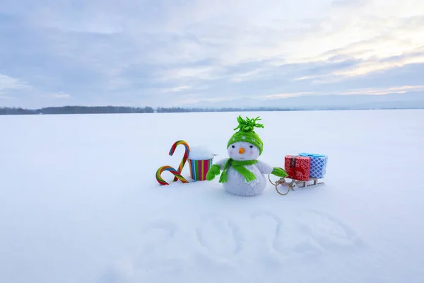 크리스마스 작곡. 썰매, 선물 상자 화려 한 바구니를 들고 있는 눈 사람. 줄무늬 사탕이야. 해피 뉴이어 2020. 잔디는 눈으로 덮여 있다. 아름다운 겨울날. — 스톡 사진