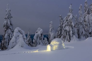 Gece kışı dağ manzaraları. Igloo karlı çimlerin üzerinde duruyor. Işıklı ev. Karpat Dağları, Ukrayna, Avrupa.