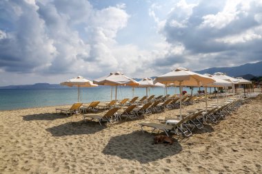 Güverte sandalyeleri ve şemsiyeleri karantinadan sonra turistleri bekleyen çöl sahilleri. Muhteşem beyaz kum, deniz ve dağ. 2020 yaz seyahati. Yunanistan Girit adasında rahatla.