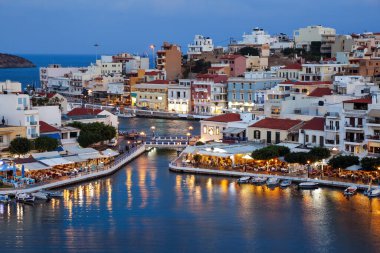 Liman kenti Agios Nikolaos 'un bir panoraması. Gece denizi manzarası, ilginç manzaralar, renkli evler, kafenin sahil manzarası. Yunanistan 'da popüler bir turizm beldesi.