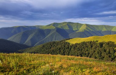 İnanılmaz bir bahar dağı manzarası. Doğa manzarası. Bulutlu dramatik gökyüzü. Turistik bir yer. Yaz dönemi duvar kağıdı arka planı. Doğanın yeniden doğuşu kavramı. Gezegenin yeniden canlanması..