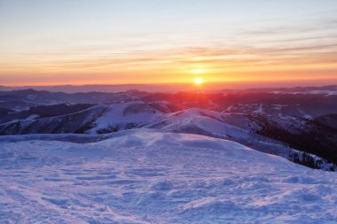 Soğuk kış sabahı. Turuncu bulutlu inanılmaz bir gökyüzü. Fantastik gün doğumu dağı aydınlatıyor. Duvar kağıdı arka planı. Konum: Carpathian, Ukrayna, Avrupa.