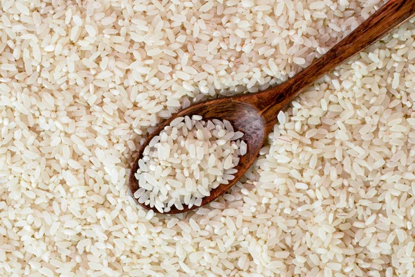 Rice background with wooden spoon close-up. The view from top. — Stock Photo, Image