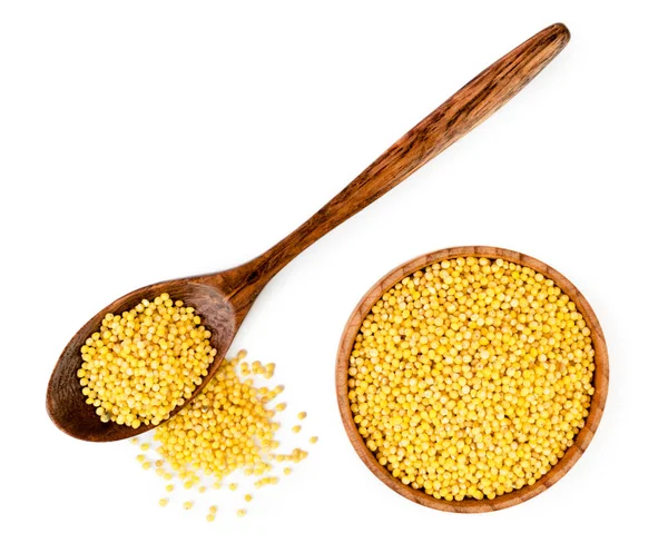 Millet in wooden spoon and plate on a white. The form of the top. — Stock Photo, Image