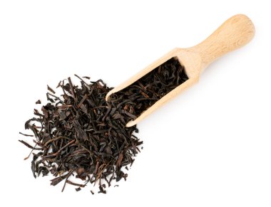 Kurutulmuş siyah çay yaprakları beyaz bir tahta kaşık dökülen. Üst formu.
