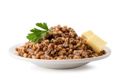 Bir tabakta haşlanmış karabuğday maydanoz yaprağı ve tereyağı küpleri beyaz. Izole.