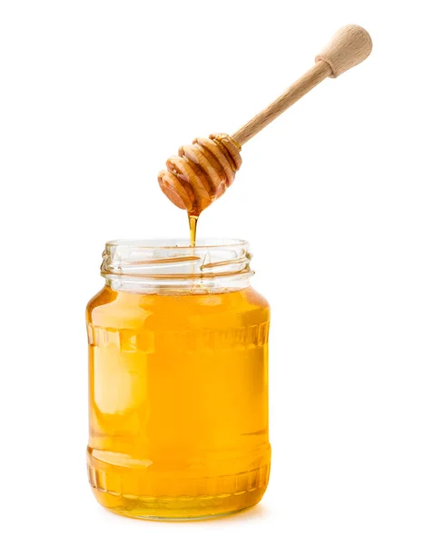 Honig fließt von einem Holzstab in ein Glas auf einem weißen, isolierten. — Stockfoto