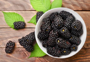 Ahşap bir arka planda yeşil yapraklı böğürtlen. Yukarıdan görünüm