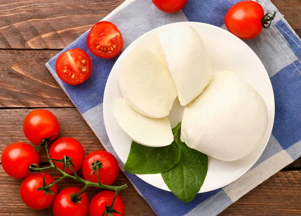 Mozzarella, kiraz domatesleri ve ahşap arka planda bir tabakta ıspanak. Yukarıdan görünüm — Stok fotoğraf