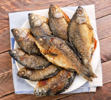 Ahşap bir arka planda tabakta kızartılmış sazan balığı. Yukarıdan görünüm