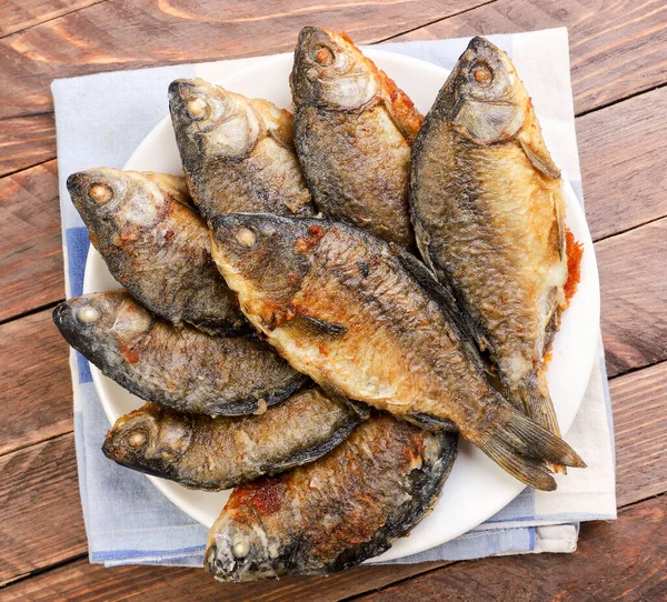 Ahşap bir arka planda tabakta kızartılmış sazan balığı. Yukarıdan görünüm