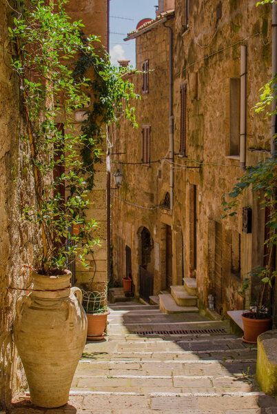 Old courtyard in Pitigliano with vases with flowers on the stairs. italy