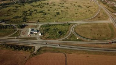 Ulaştırma Kavşağı görüntülerini hava dron yaz, çapraz yol kavşağı gün görünümü yukarıdan yeşil ağaç daire yol ile trafik, yakın bir buğday alandır. Yukarıdan aşağıya trafik sıkışıklığı görünümünü.