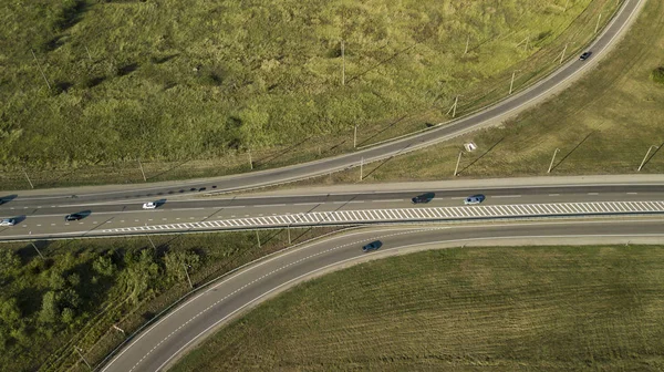 Summer aerial drone photo of transport junction, traffic cross road junction day view from above with green tree circle road, near is a wheat field. Top down view of traffic jam.