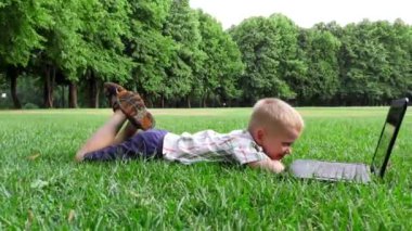 6 yaşındaki çocuk laptop, yüzü neşeli duygular bir çim üzerinde bırakır