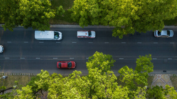 Воздушный беспилотный полет сверху Вид на оживлённое шоссе в час пик. Вид с воздуха на автомобильный перекресток, движение в часы пик с автомобилями на дороге, пролет под деревьями
.