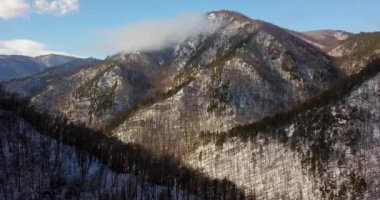 Dağ Güneş doğarken kalın bulutların üzerinde yükselen engebeli kar kaplı