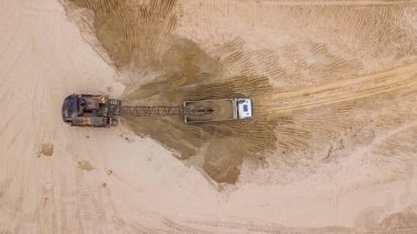 Ekskavatörün görüntüsünü aşağı yaslamak kamyona kum döker. Şantiyede.