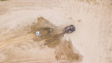 Ekskavatörün görüntüsünü aşağı yaslamak kamyona kum döker. Şantiyede.