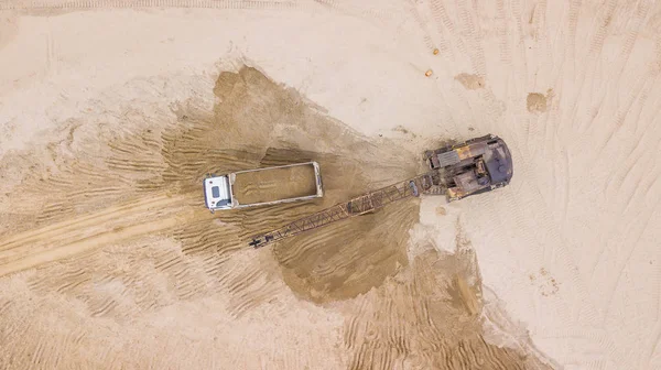 Tod vue vers le bas de la pelle verse du sable dans le camion. Sur le chantier . — Photo