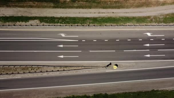 Directy boven close up van weg, asfalt, witte pijl borden die richting, weg van de snelweg. — Stockvideo