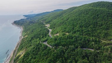 Drones Eye View - Soçi, Rusya yüksek dağ geçidinden dolambaçlı yol. Büyük yol gezisi yoğun ormanda yalak.
